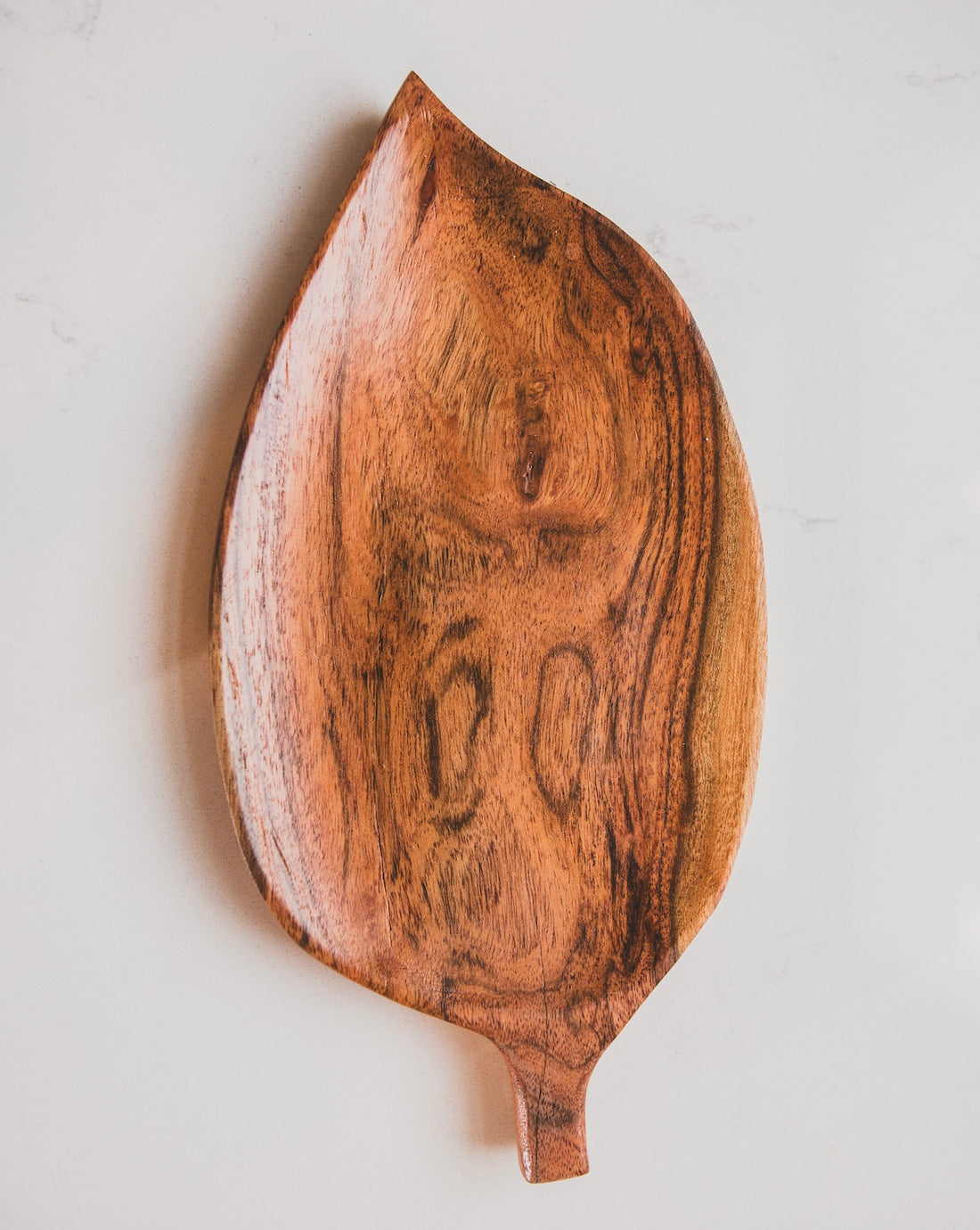 Wooden leaf-shaped cutting board on a light gray background