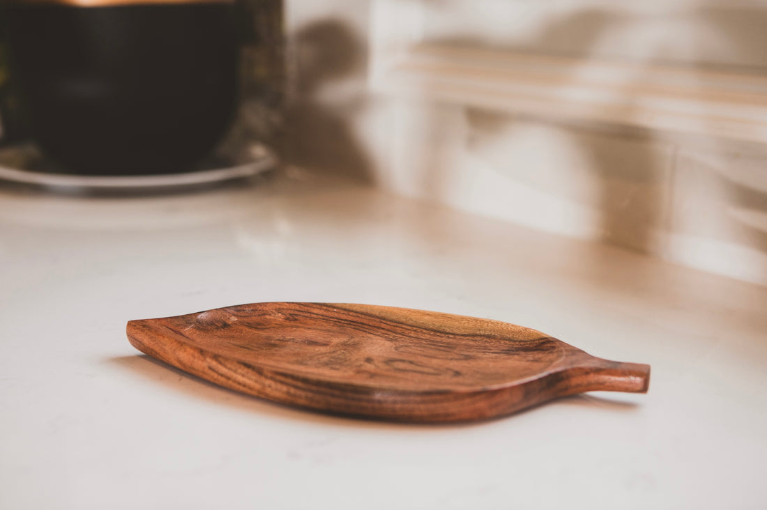 Wooden leaf-shaped coaster on a light surface with a blurred background