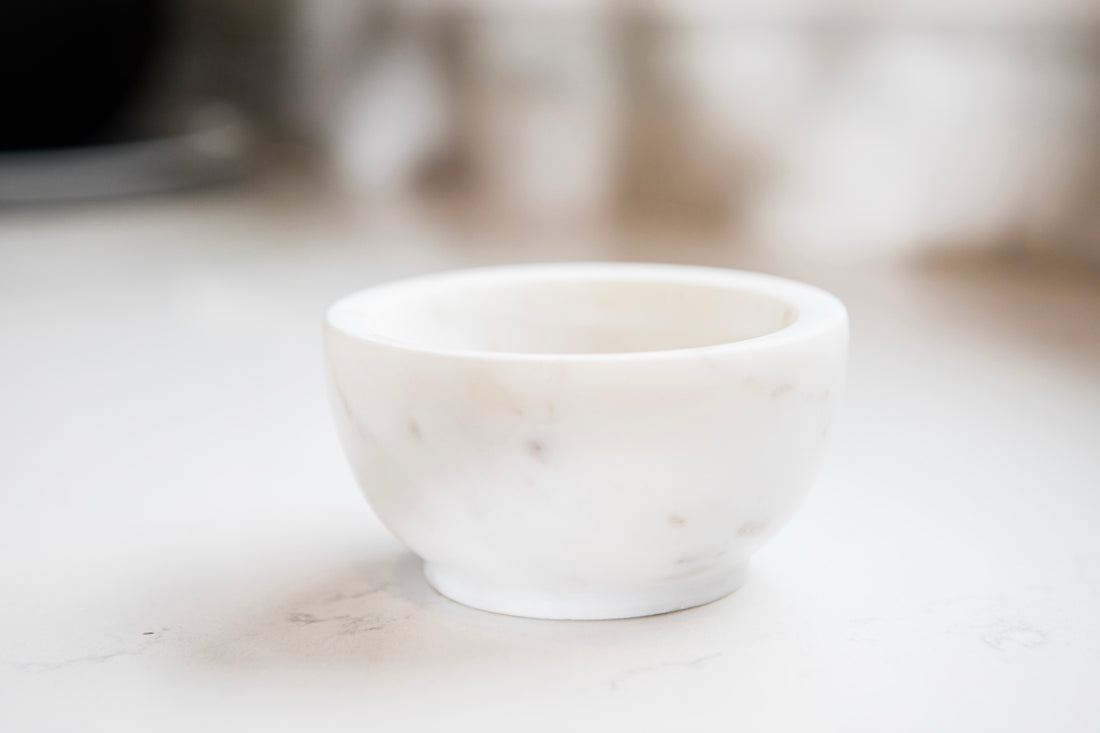 White ceramic bowl on a marble surface with a blurred background
