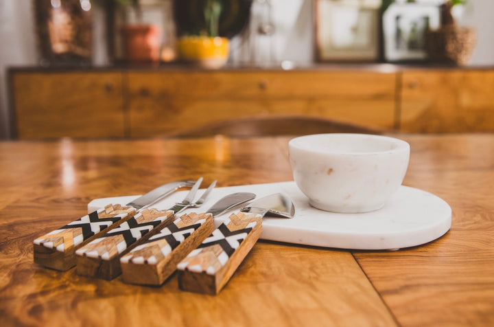 White marble cheese board with a cup on a wooden table