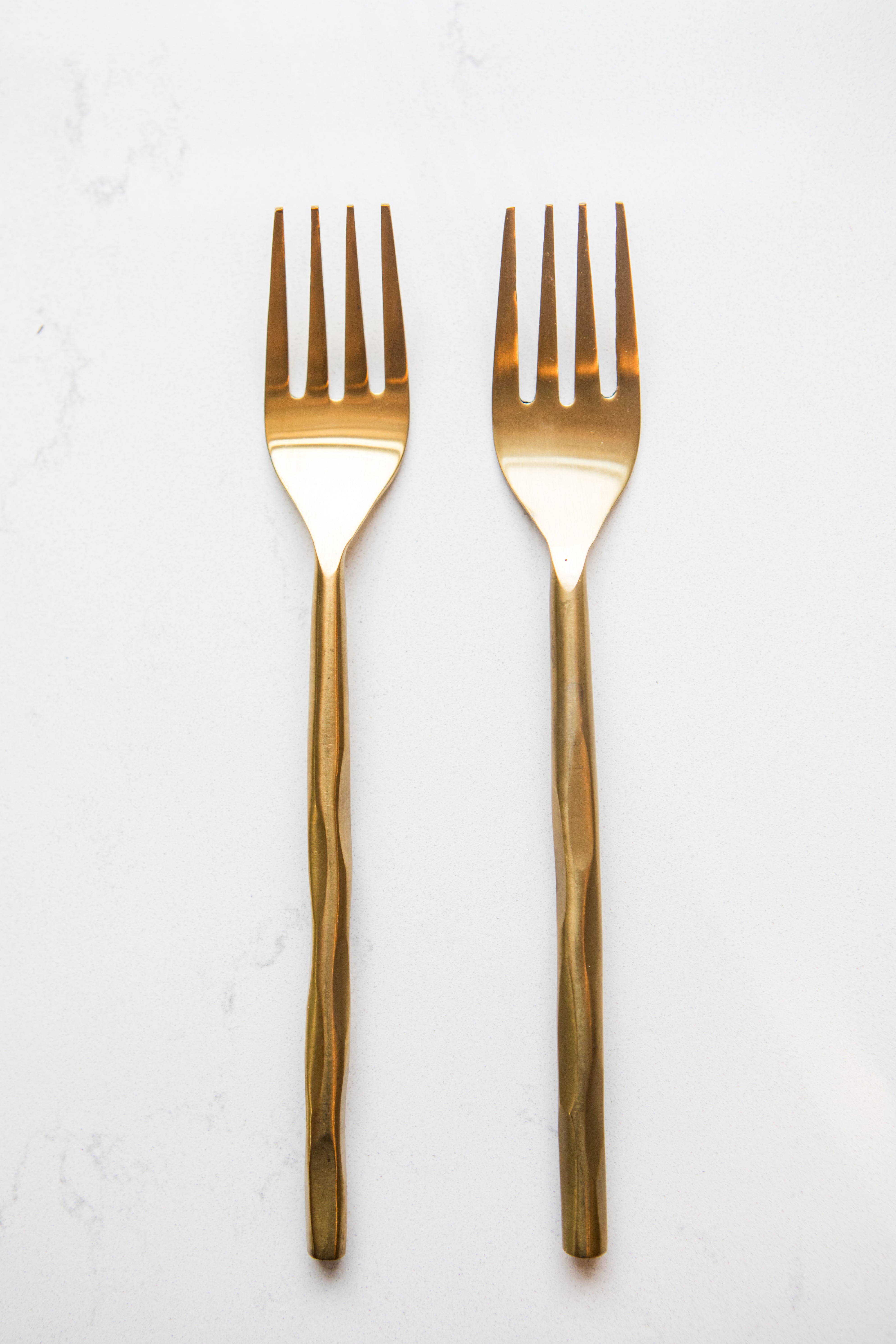 Two gold forks on a white background