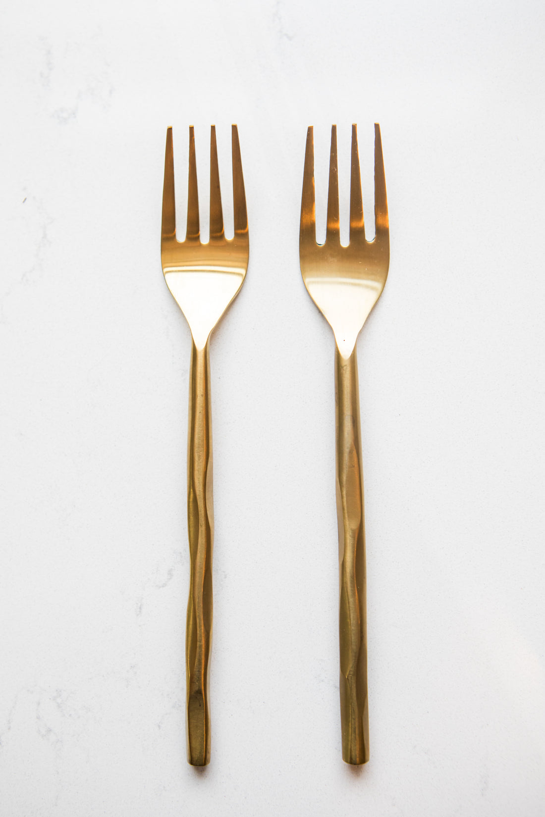 Two gold forks on a white background