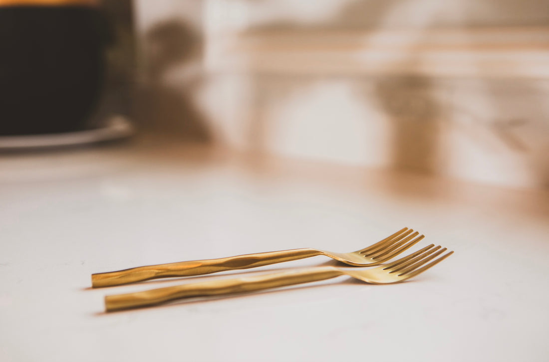 Two gold forks on a light surface with a blurred background