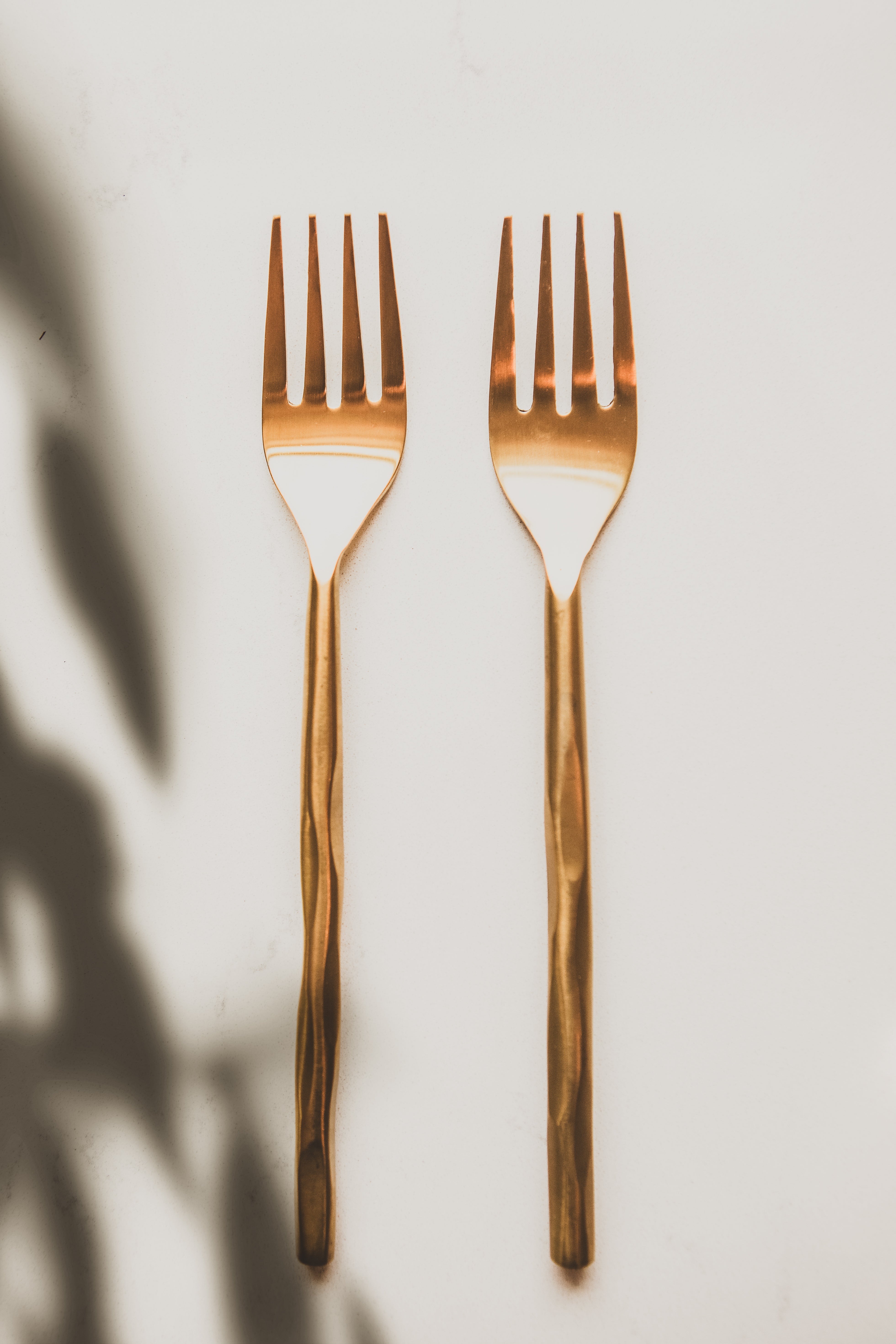 Two rose gold forks on a light background