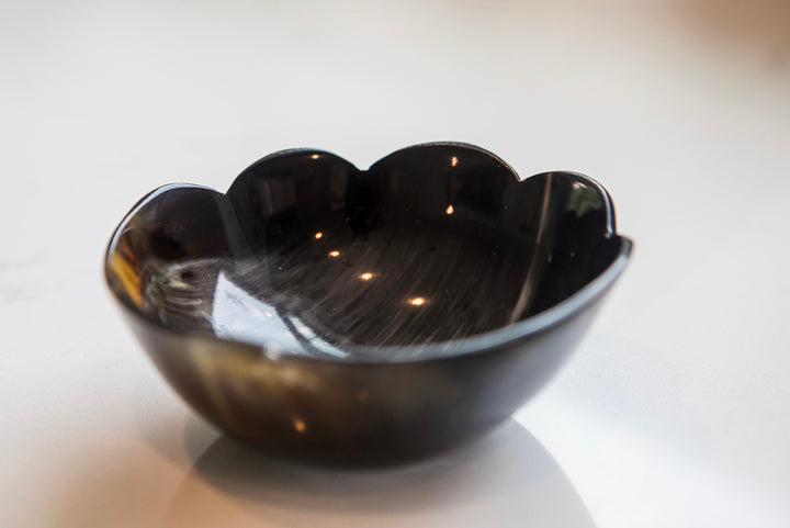 Black glass bowl on a reflective surface with a blurred background