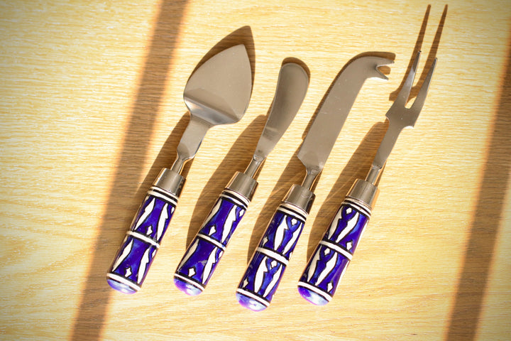 Set of four cheese knives with blue handles on a wooden surface