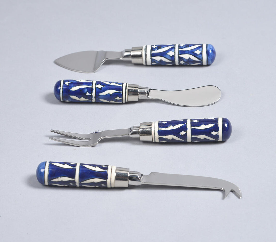 A set of cheese utensils with blue and white patterned handles and stainless steel blades, including a knife, fork, and a small opener.