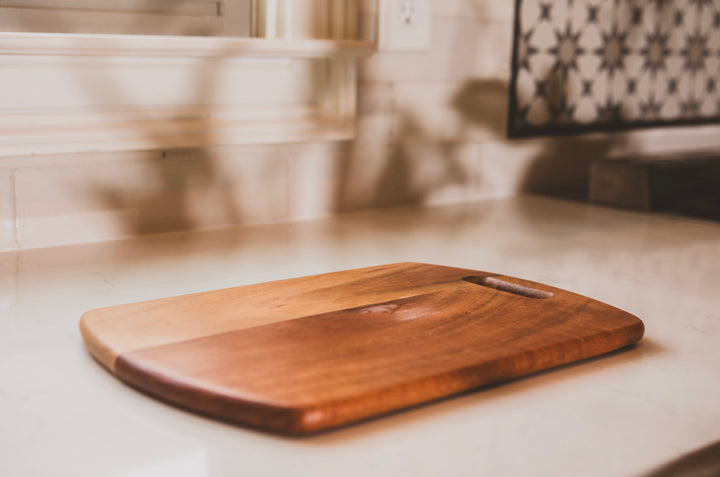 Wooden cutting board on a kitchen counter with a blurred background