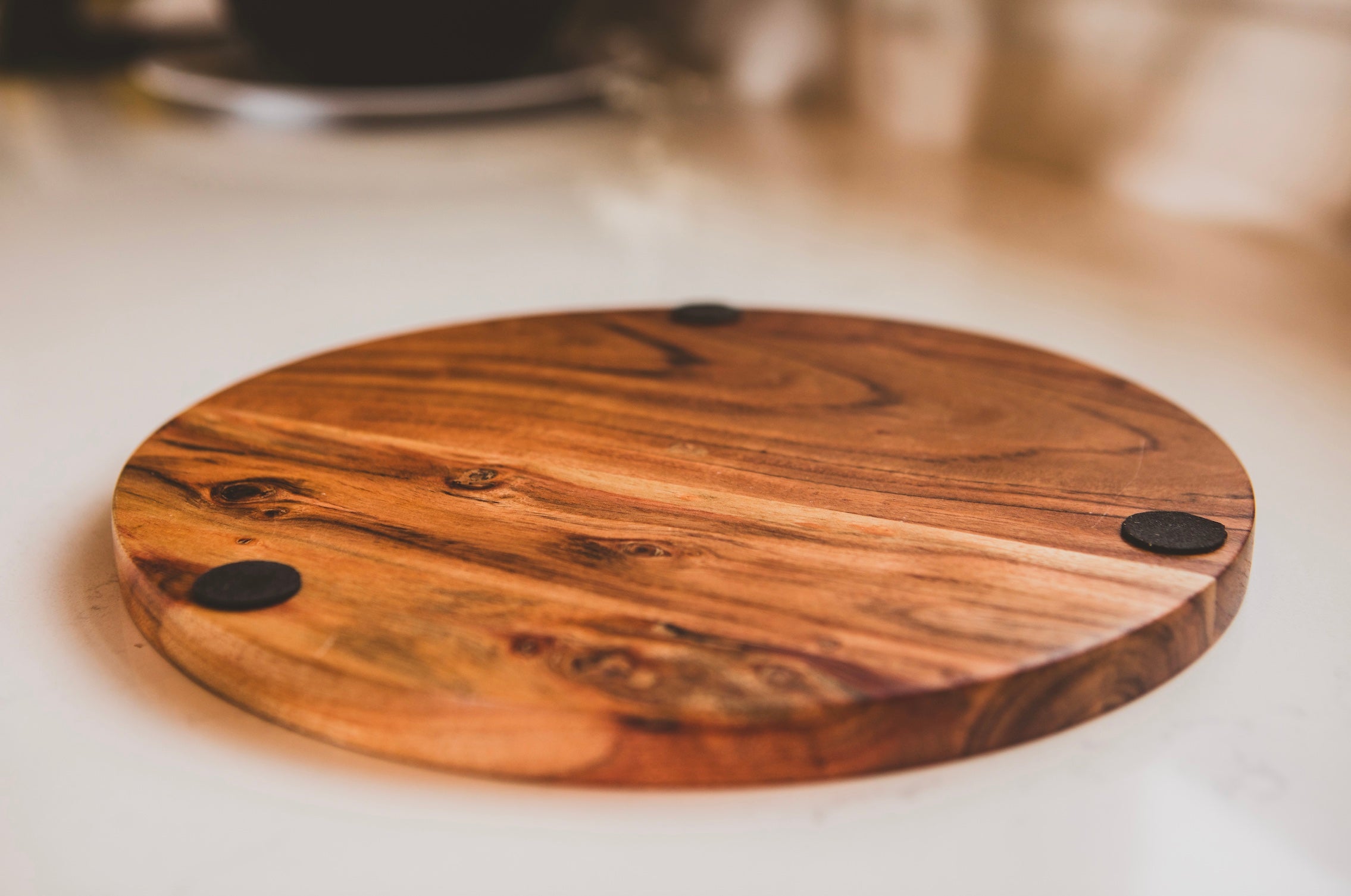 Wooden cutting board with black knobs on a white surface