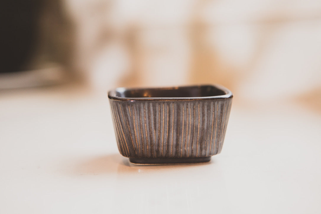 Small ceramic container with textured surface on a light background
